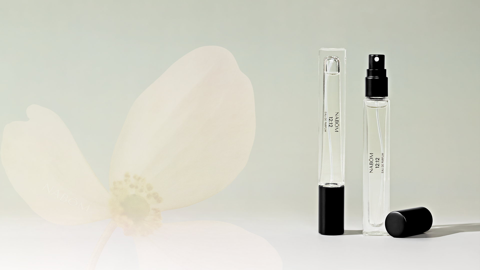 Two small perfume bottles with black caps on a light green background